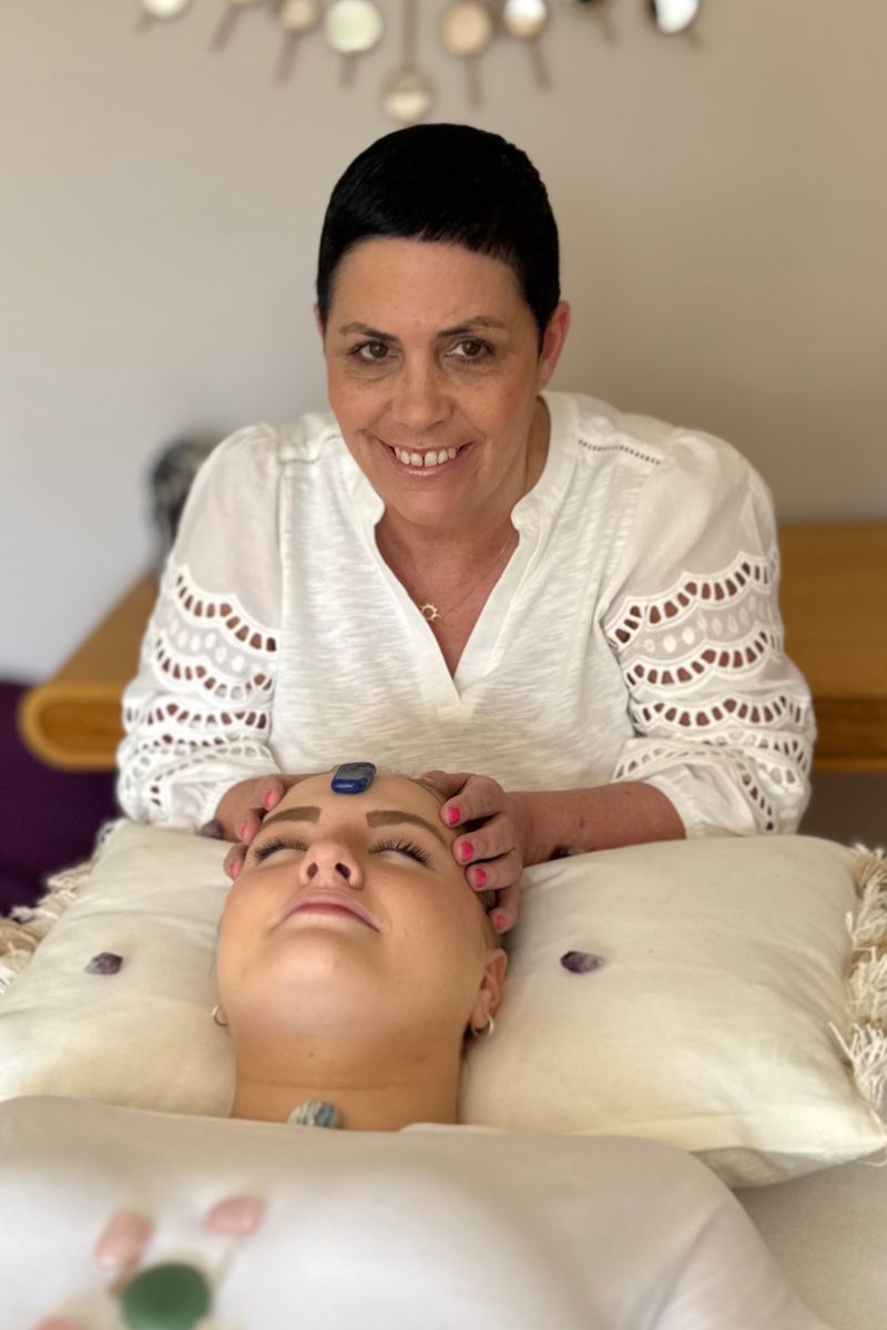 Nikki Hastings, holistic therapist at Sunshine Holistics in Hertford, smiling during a crystal chakra balance treatment
